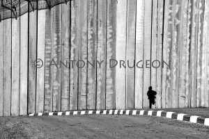 Un petit garçon (5 ans) court le long du mur de séparation israélien haut d'environ 10 mètres.