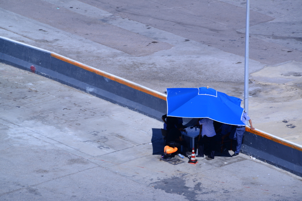 Des hommes sous un parasol sur le quai